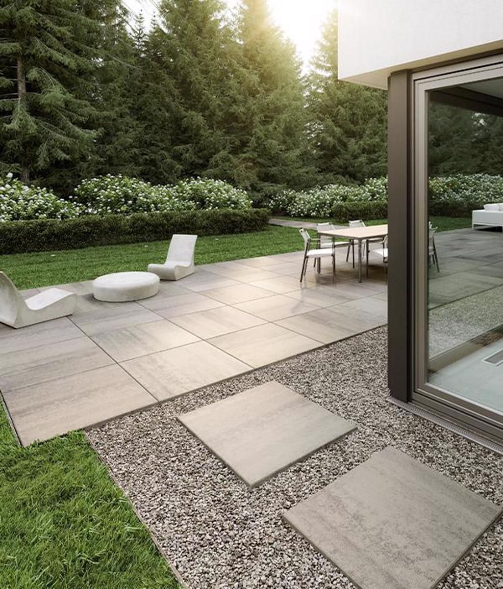 A patio with a table and chairs in the backyard of a house.