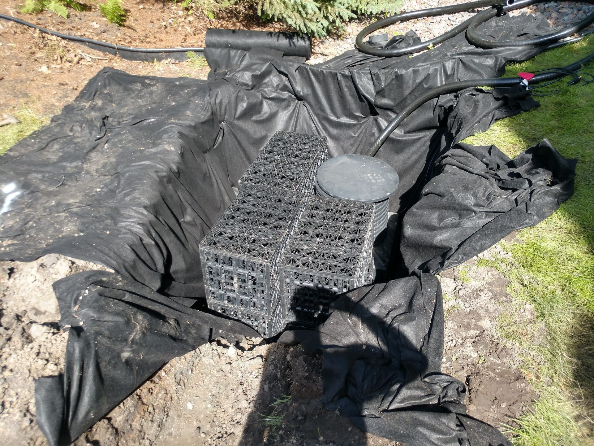 Dry well with outdoor sump pump basin connected into city storm sewer being installed at the end of French drain