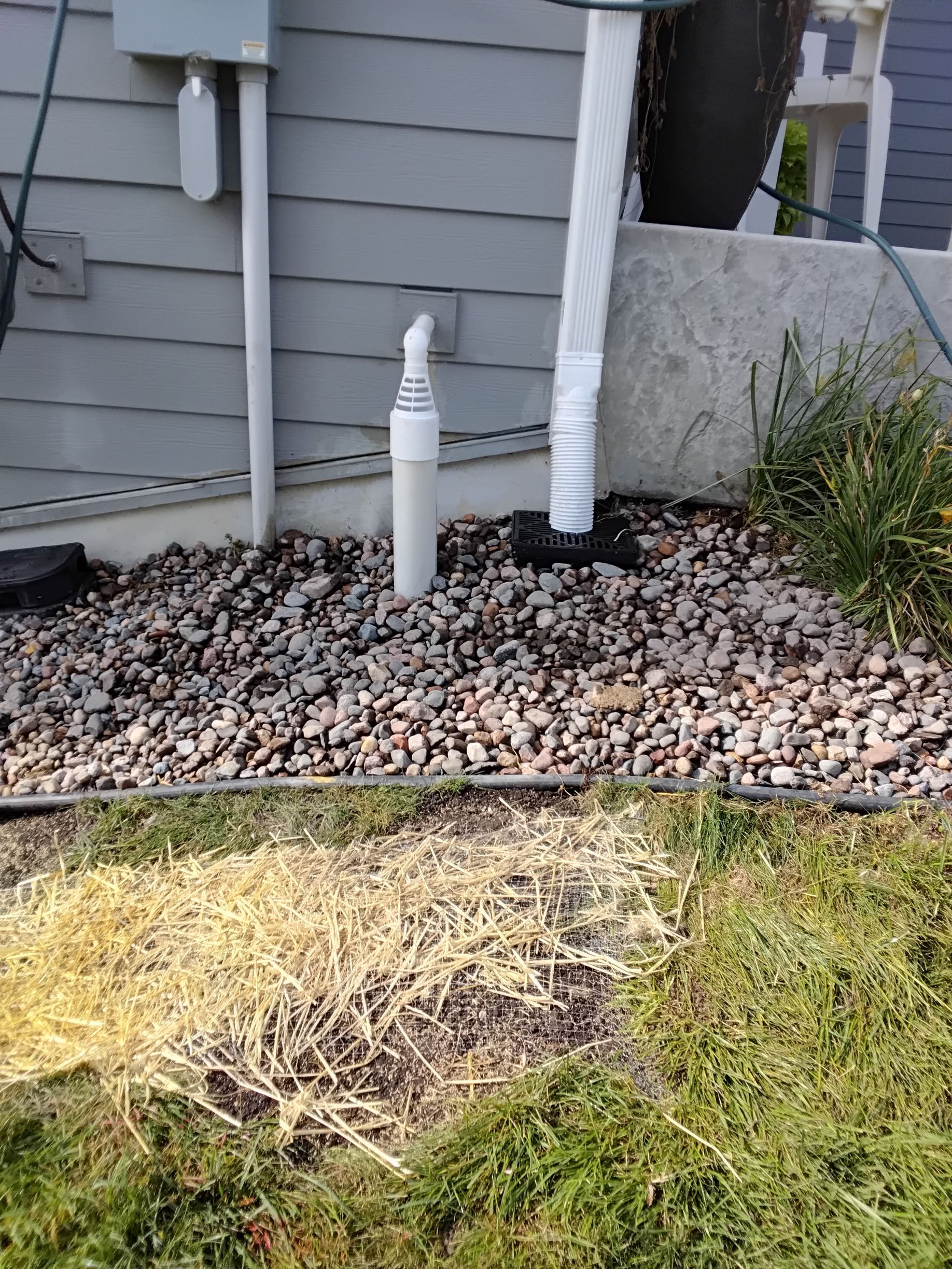 New underground sump pump discharge line with PVC piping and air gap installed beside an underground gutter system connected to a catch basin.