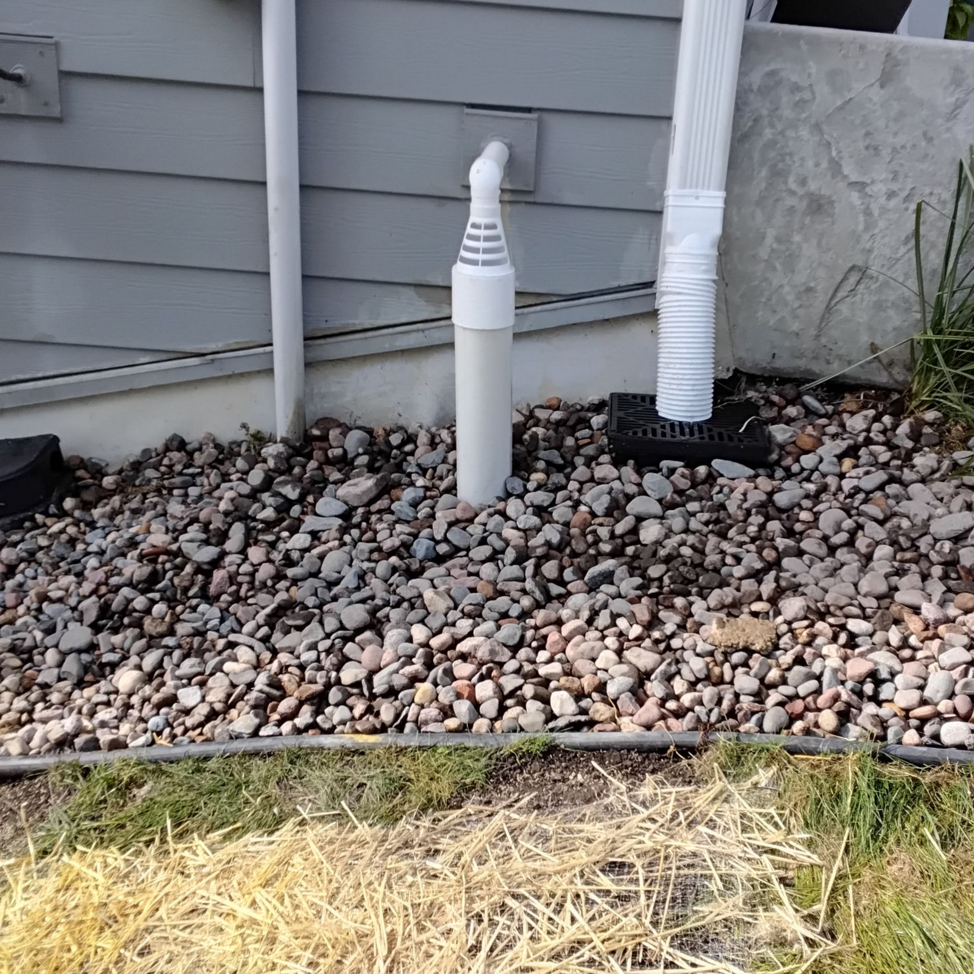 Integrated drainage system in Plymouth, MN combining sump pump discharge and underground downspouts into a shared pipe that safely outlets away from the home.
