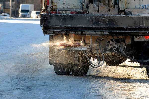 A snow plow is driving down a snow covered road.