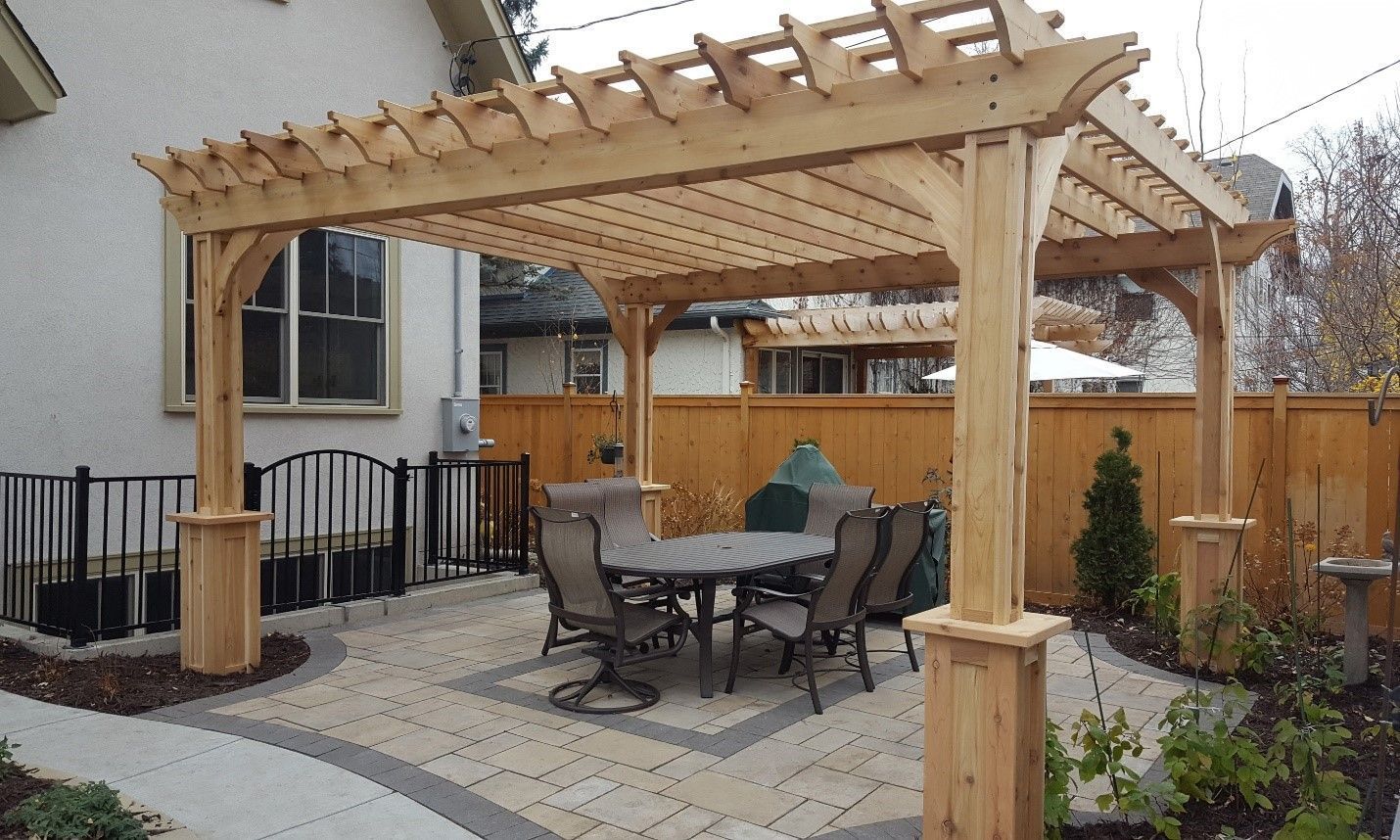 A wooden pergola with a table and chairs underneath it