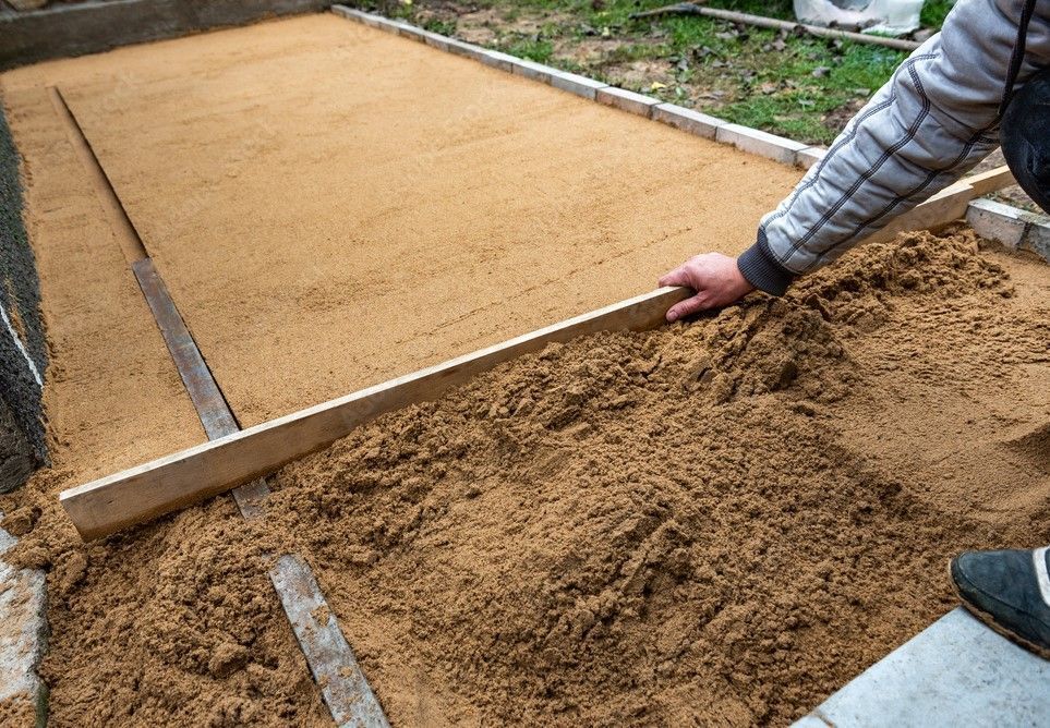 A person is spreading sand on a concrete surface.