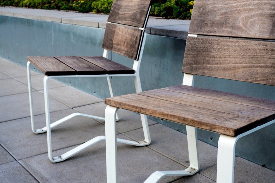 Two wooden chairs are sitting next to each other on a sidewalk.