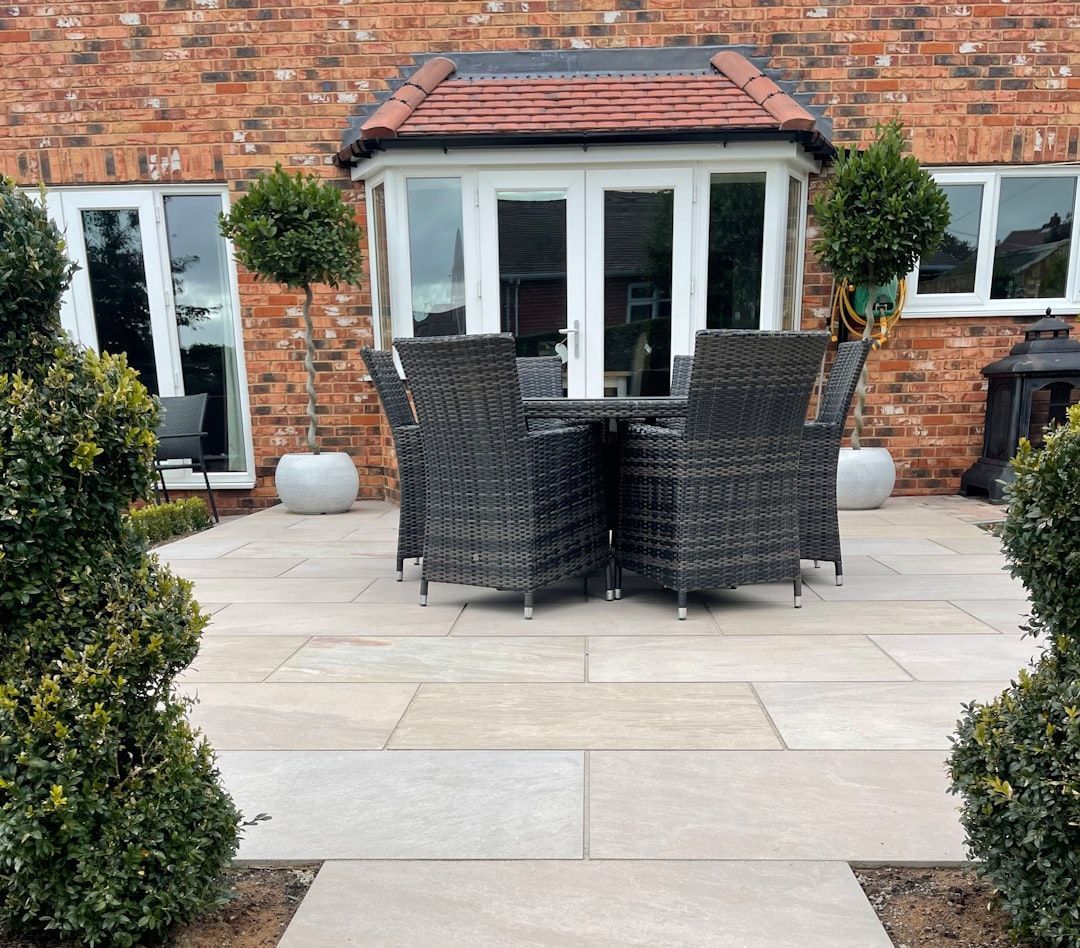 A patio with a table and chairs in front of a brick building.