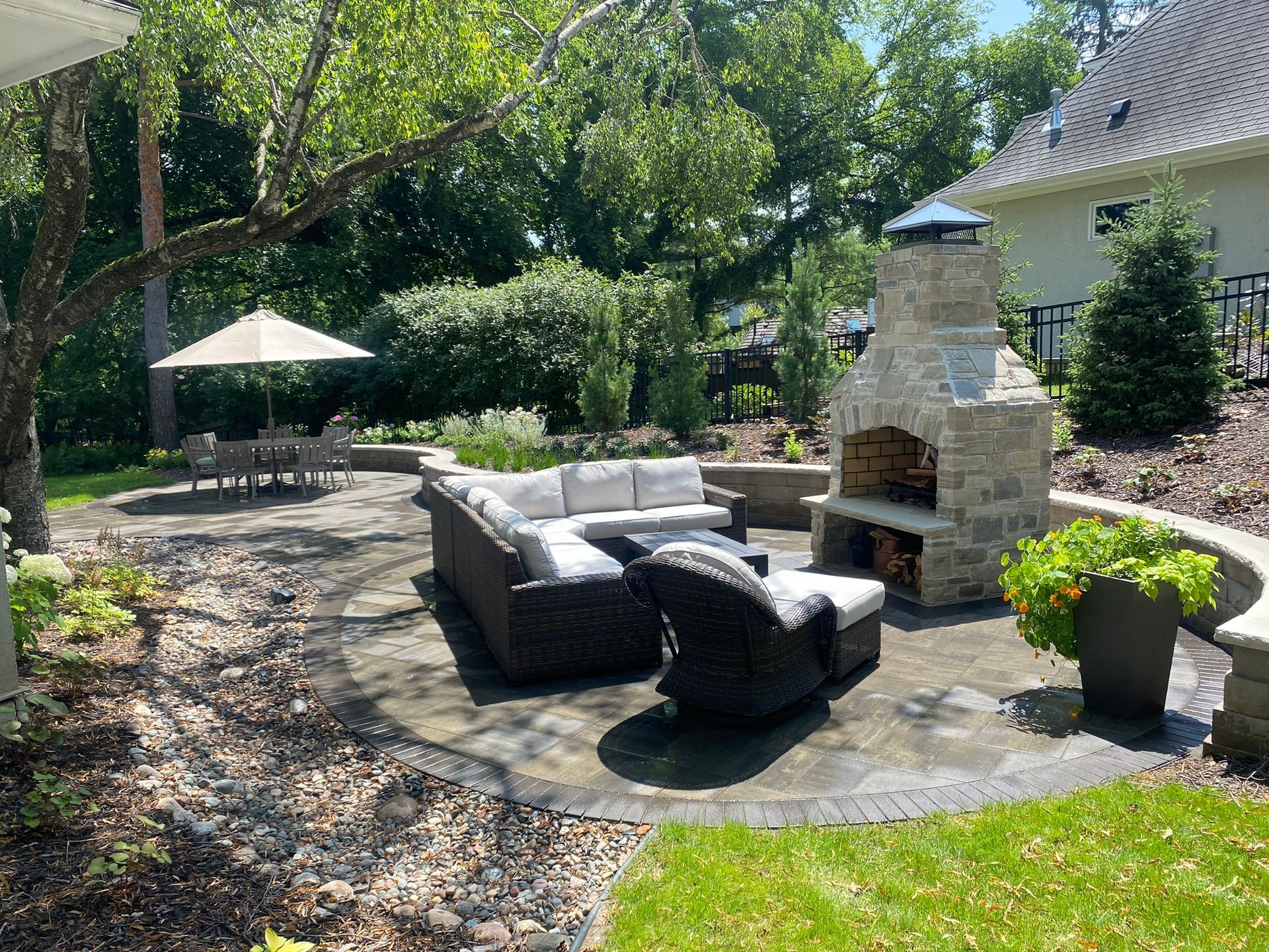 Patio design and installation example Minnetonka MN KG Landscape featuring a custom natural stone outdoor fireplace with nice wicker furniture 