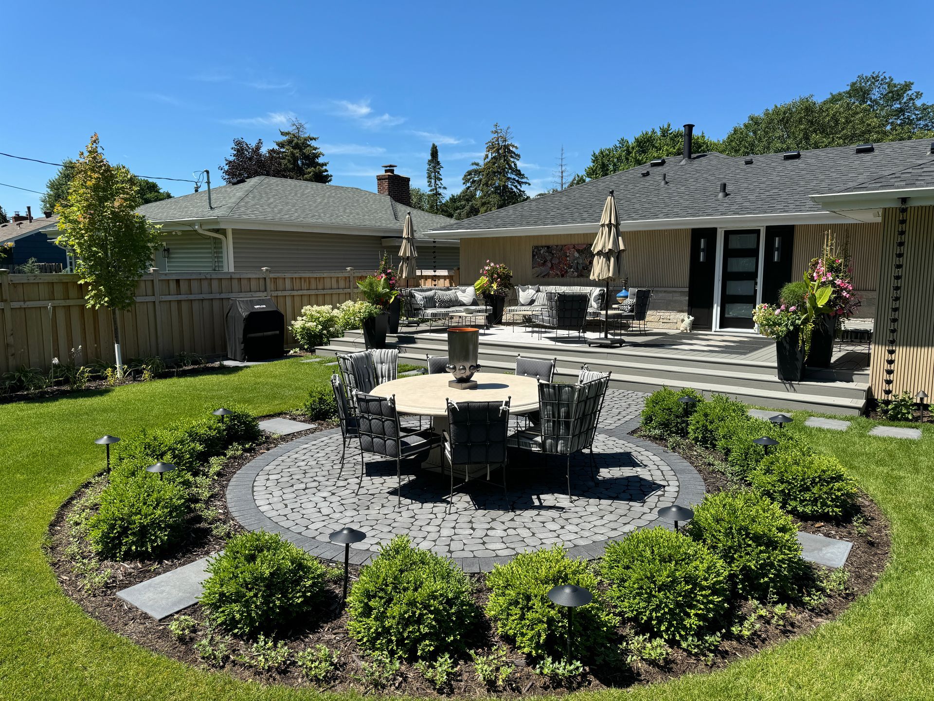 gorgeous backyard landscaping design by KG landscape outdoor living space Edina MN lounge space table chairs grill stepping stones flower pots outdoor art modern colorful rambler  