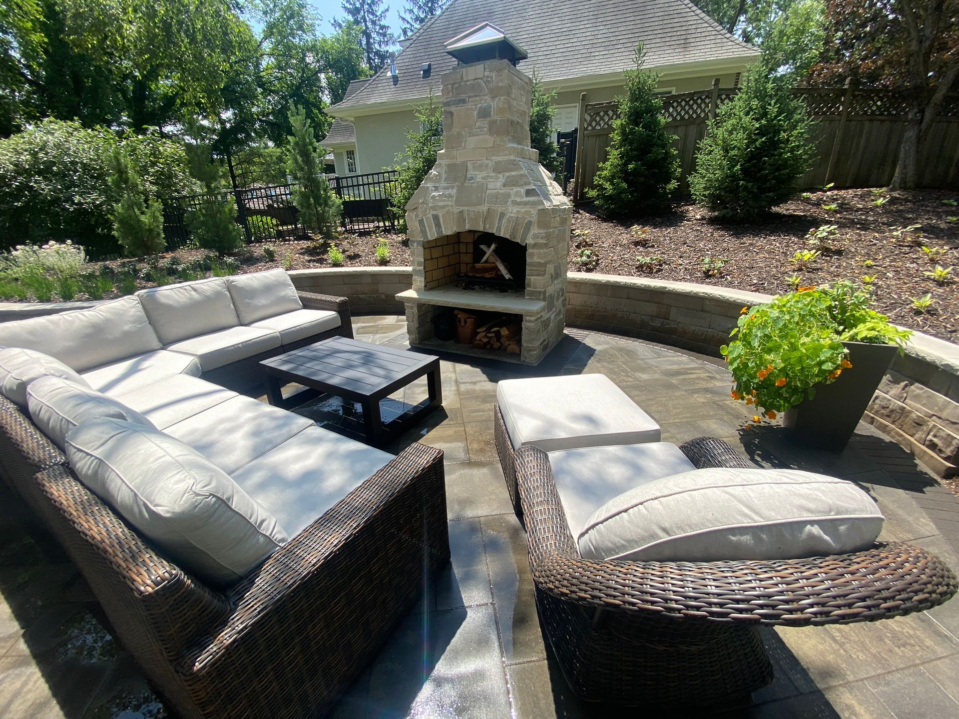 Paver Patio Minnetonka MN KG Landscape view from sitting area L shaped couch and comfortable chair looking at a custom natural stone fireplace plantings wall around the patio 