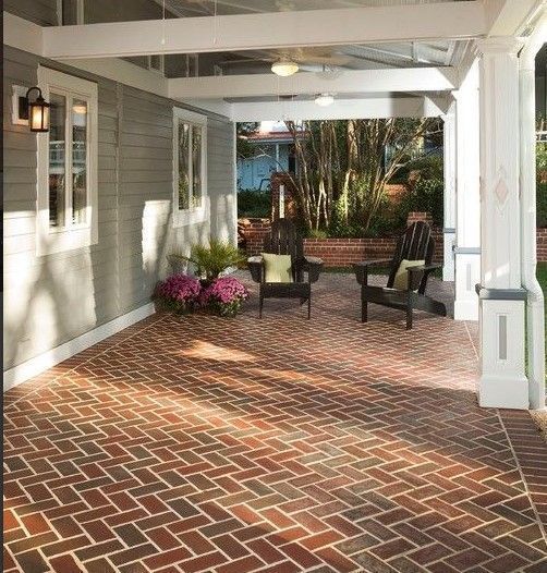 A brick patio with chairs and flowers on it