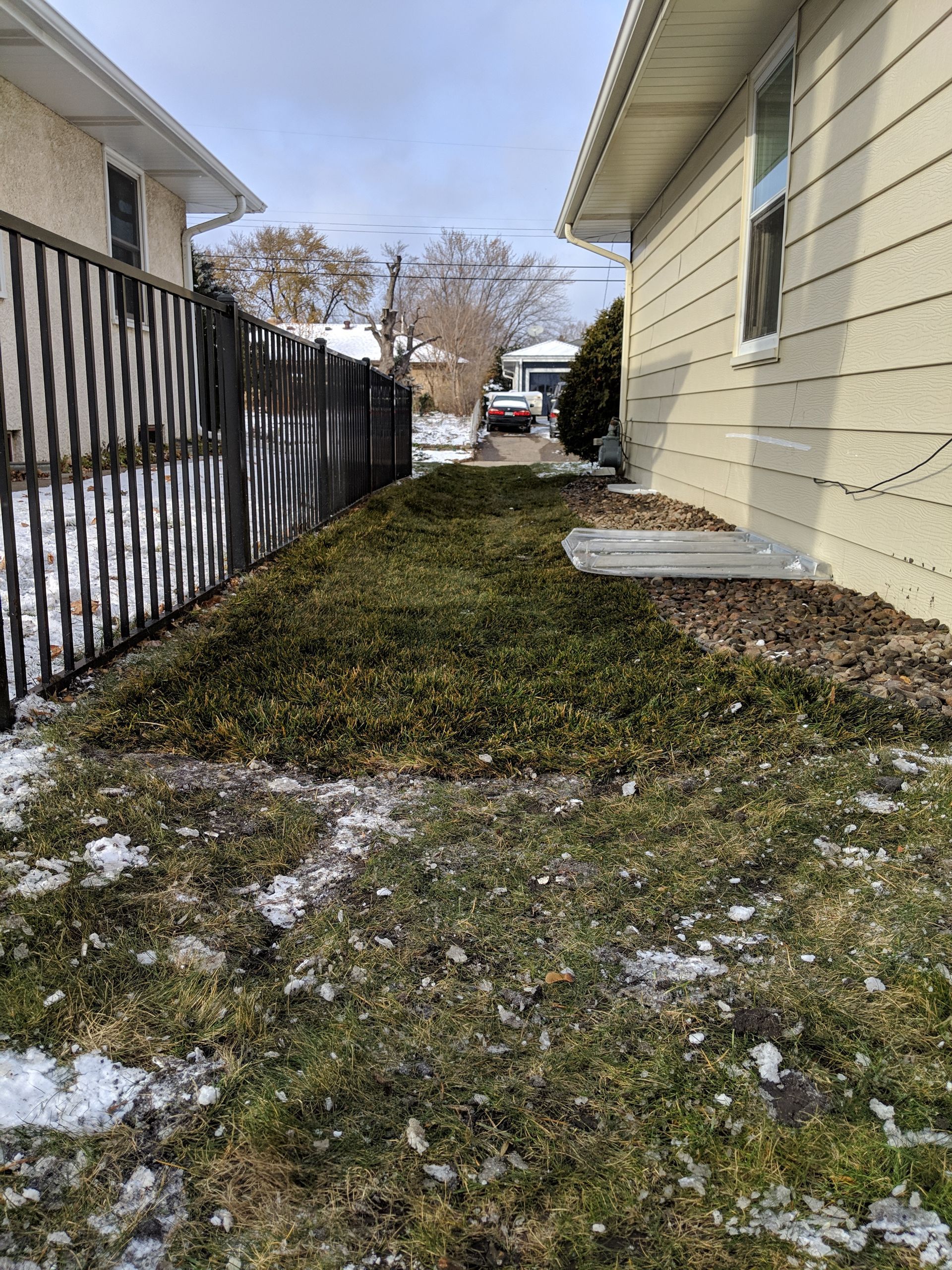 New side yard grading swale repaired with sod shows how lawn swale sends water away from house and out toward front yard