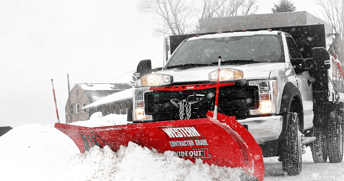 Snow plow truck plowing a snow-covered road. Red plow, white truck, and snowfall.