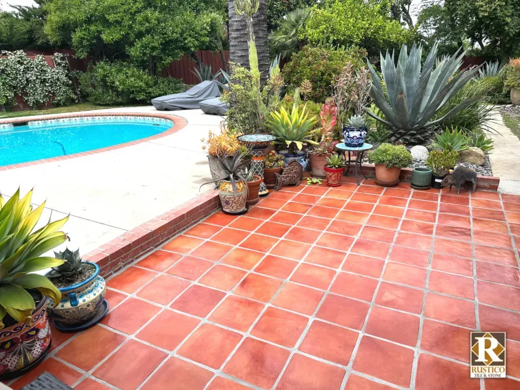 A patio with potted plants and a swimming pool in the background.