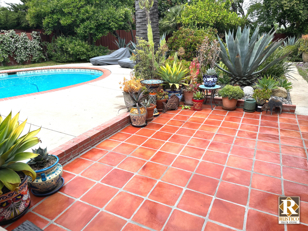 A patio with potted plants and a pool in the background