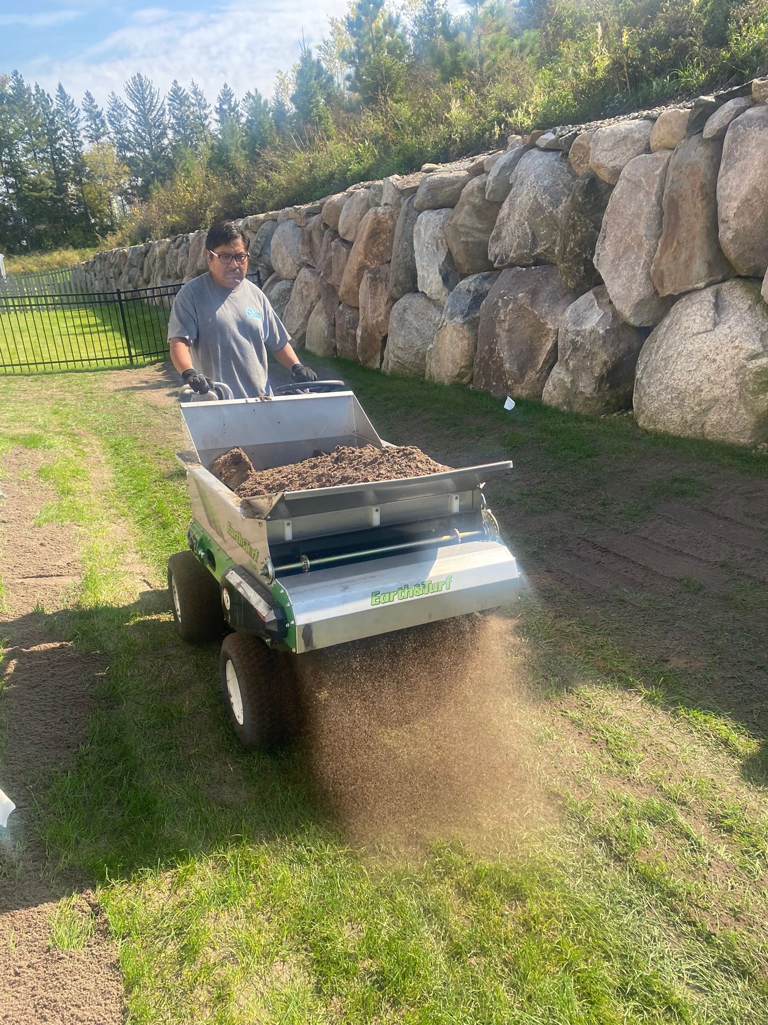 During: foreman applying topdressing soil mix in backyard 