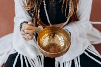 A woman is holding a singing bowl in her hands.