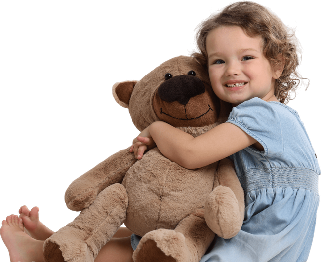 A little girl in a blue dress is hugging a brown teddy bear