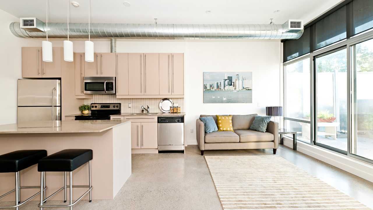 A living room with a couch and a kitchen with stools