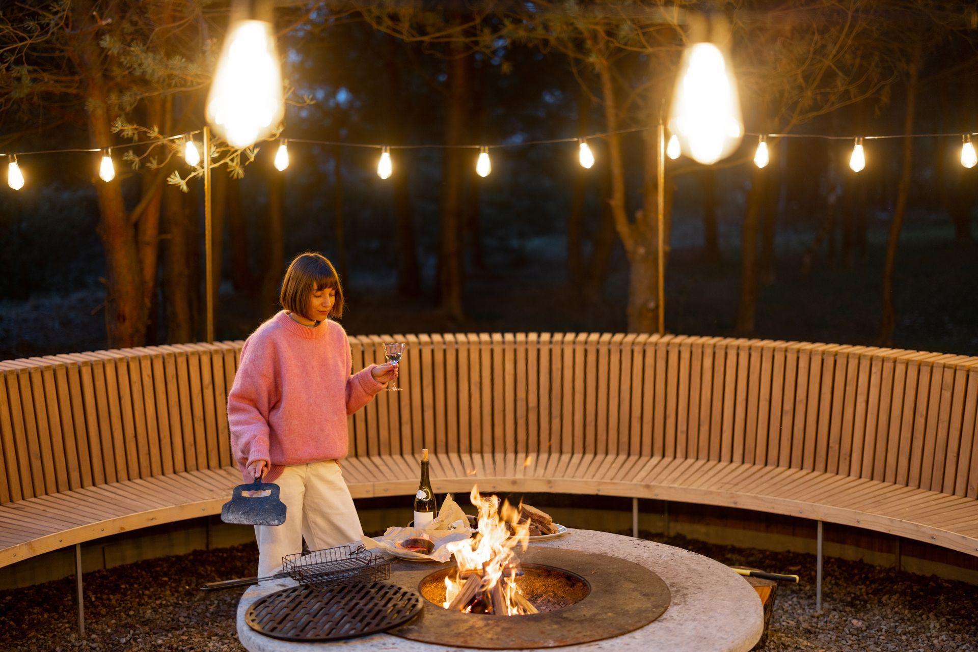 Fire pit and three gray Adirondack chairs on patio overlooking lawn.