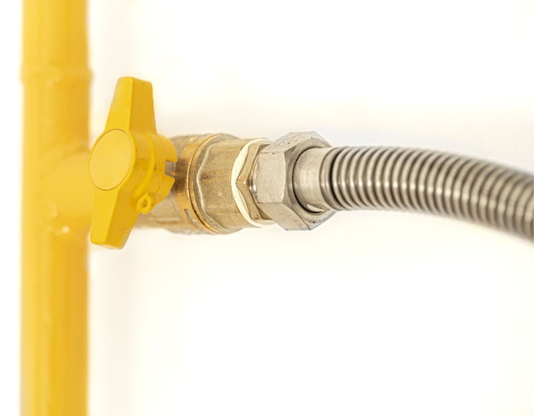 Yellow gas valve connected to a flexible metal hose.