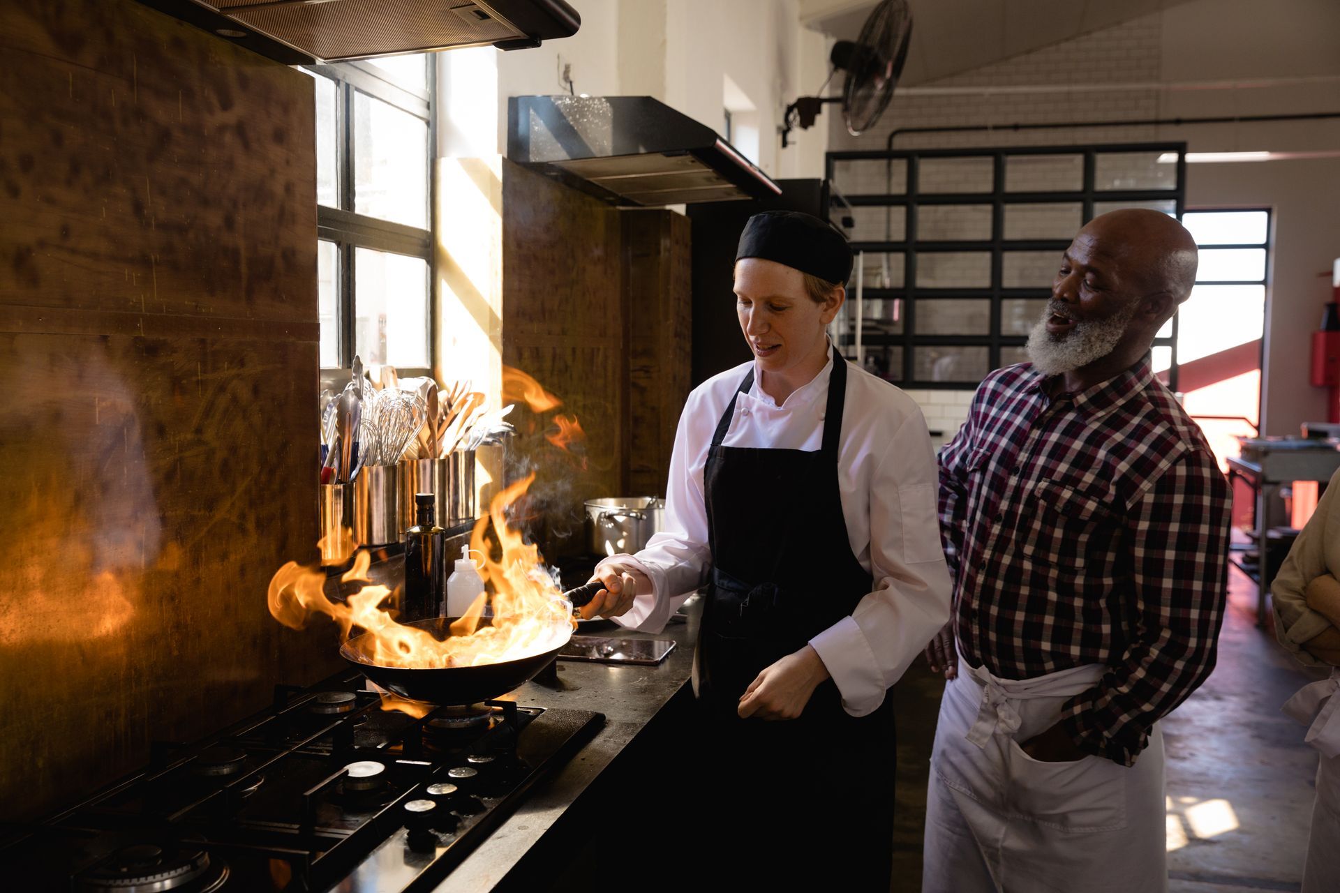 Stainless steel gas cooktop with lit blue flames, set in granite countertop above white cabinets.