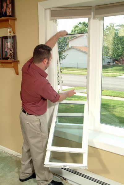 A man in a red shirt is opening a window