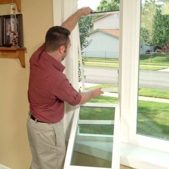 A man is installing a window in a living room.