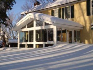 A house with a screened in porch covered in snow.