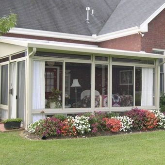 A house with a screened in porch surrounded by flowers