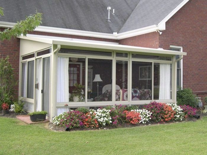 A house with a screened in porch and flowers in front of it