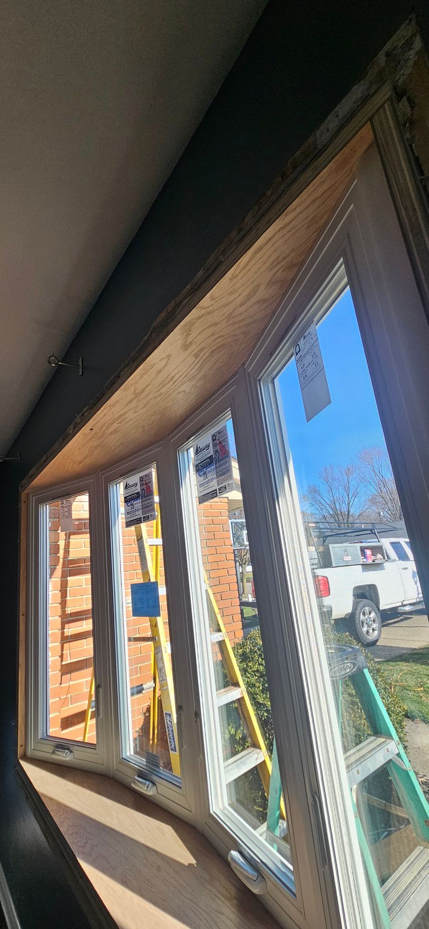 A window is being installed in a house with a ladder in the background.