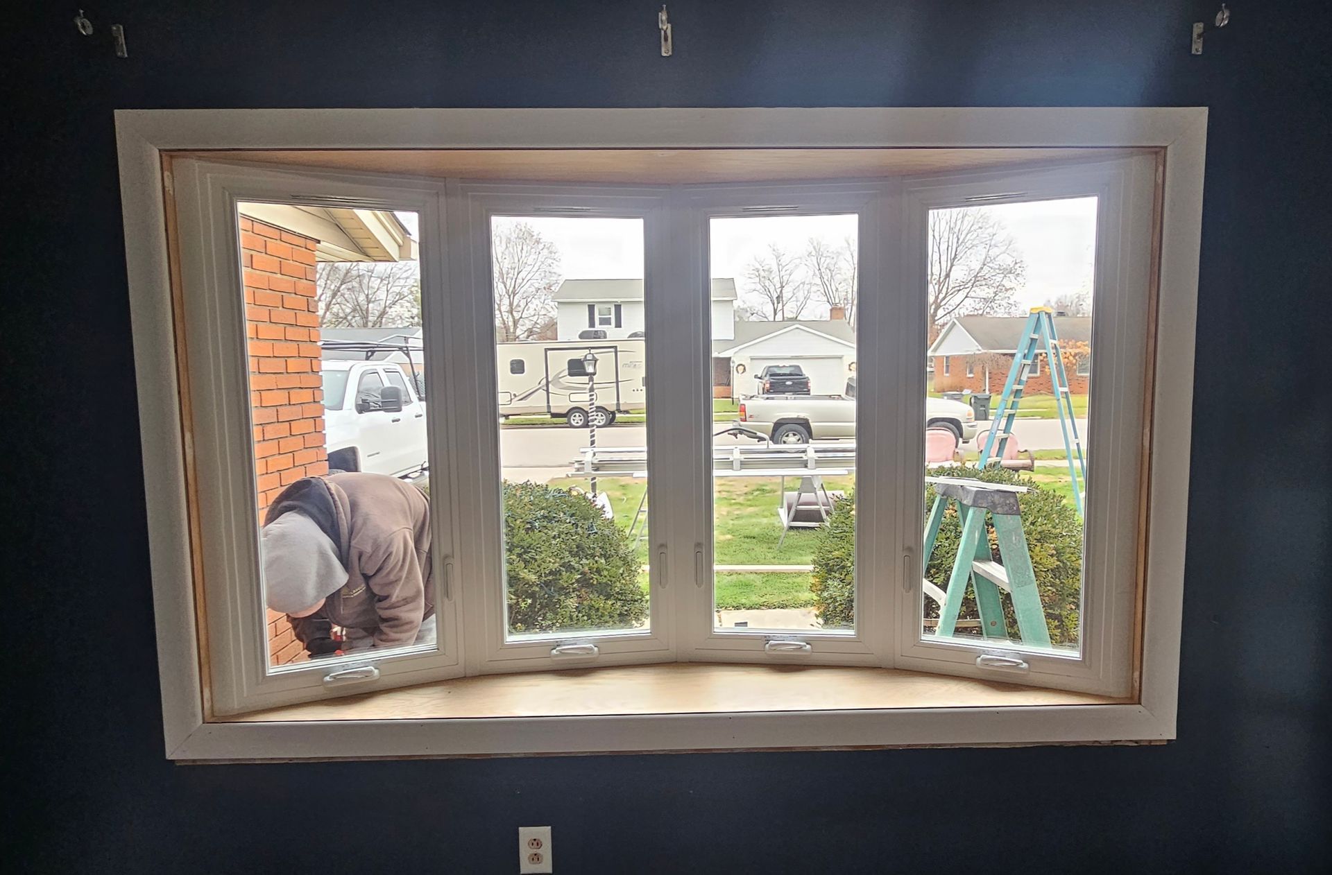 A man is working on a bay window in a house.
