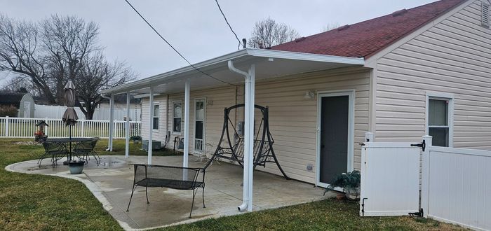 A white house with a porch and a swing in the backyard.