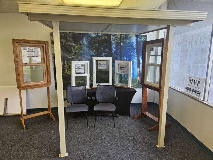 A room with chairs , a table and a display of windows.