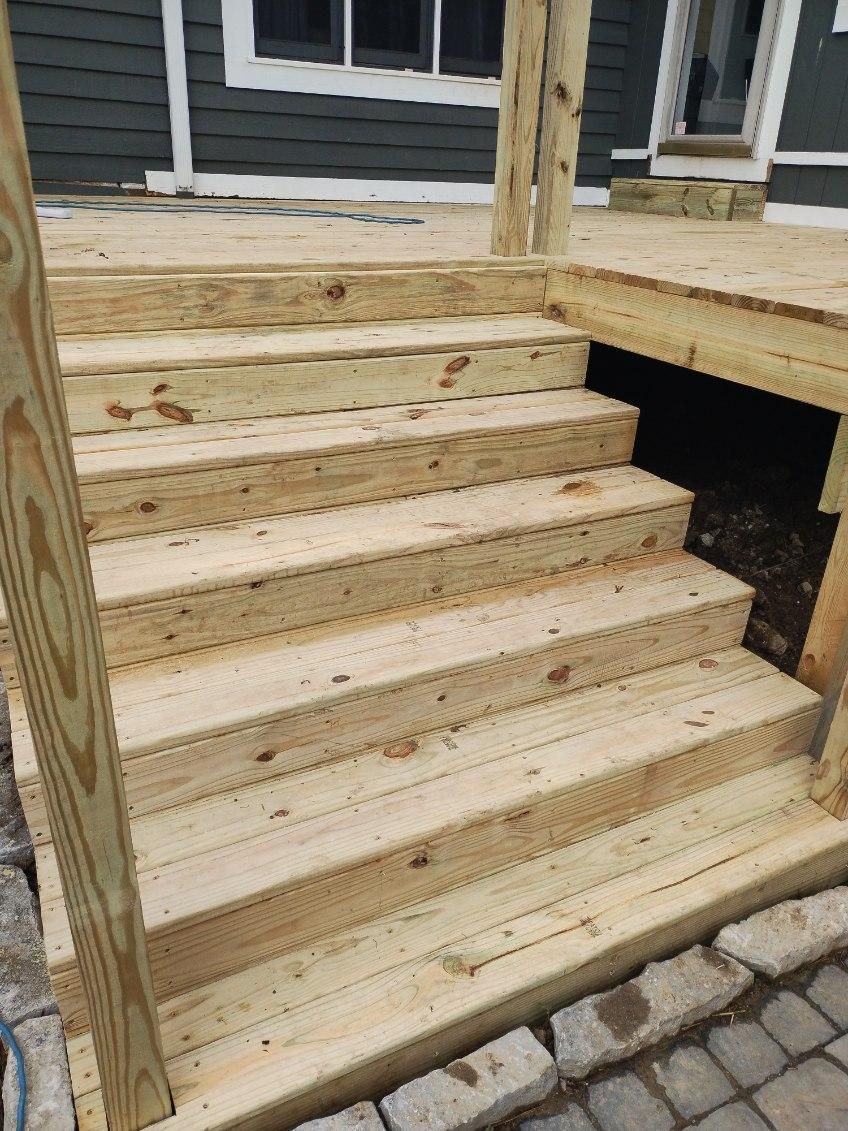 A wooden deck with stairs being built in front of a house.