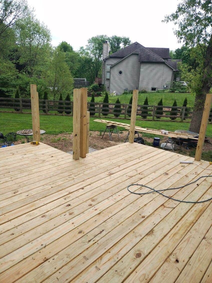 A wooden deck is being built in a backyard with a house in the background.