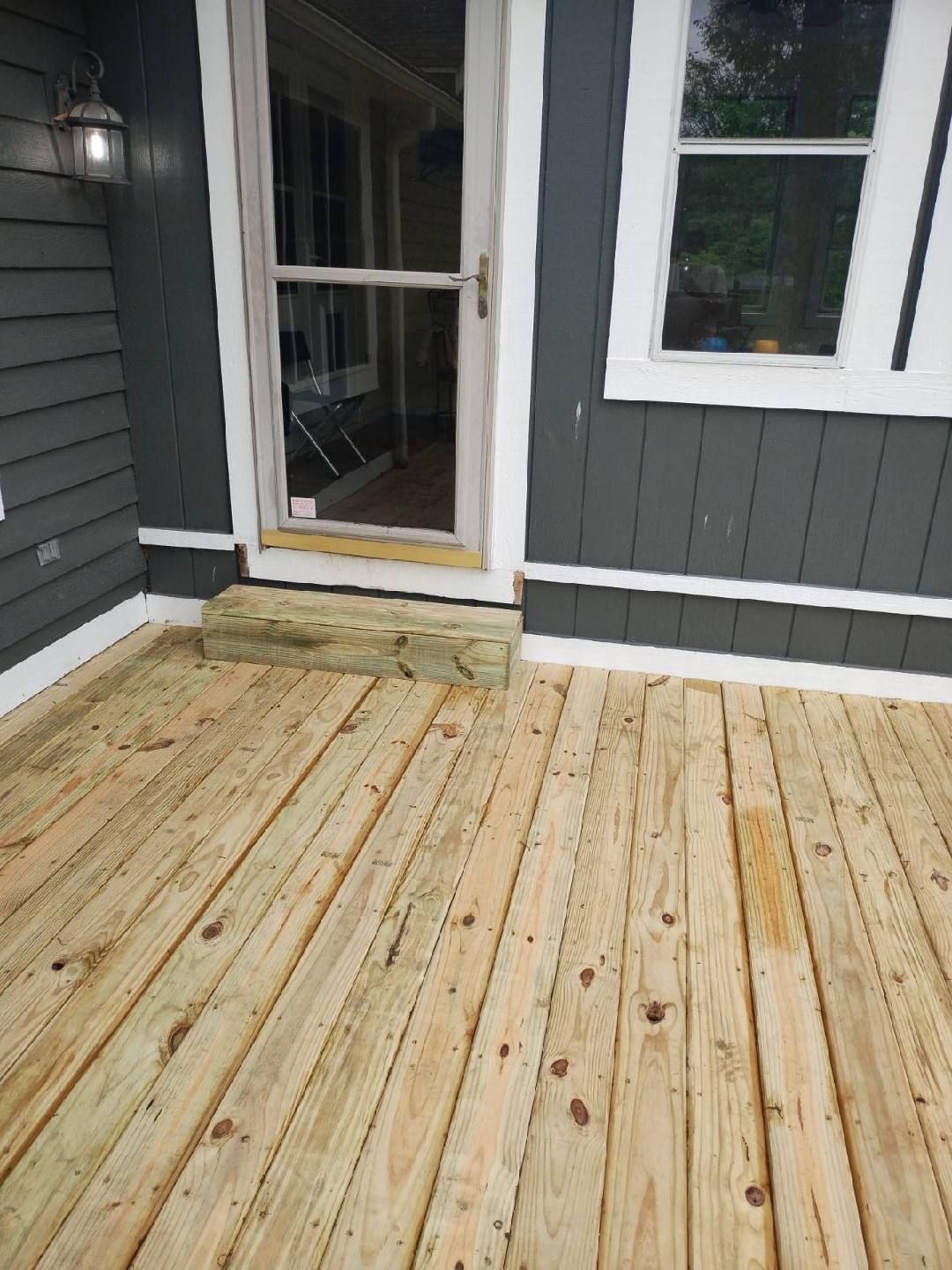 A wooden deck in front of a house with a sliding glass door.