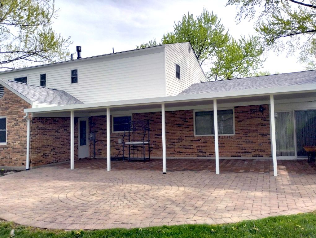 A brick house with a white roof and a covered patio