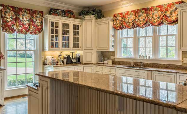 A kitchen with white cabinets , granite counter tops , and a large island.