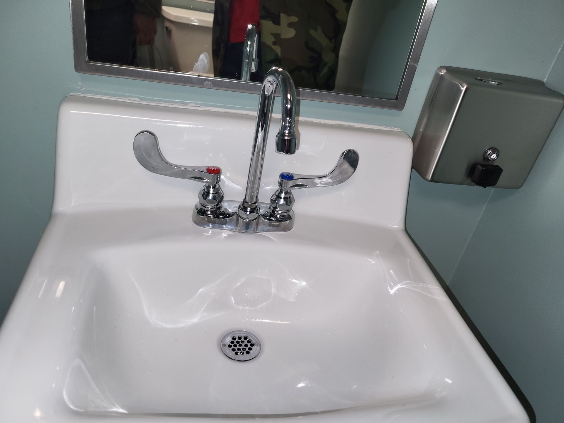 White porcelain sink with chrome faucet, red and blue handles, and a soap dispenser.