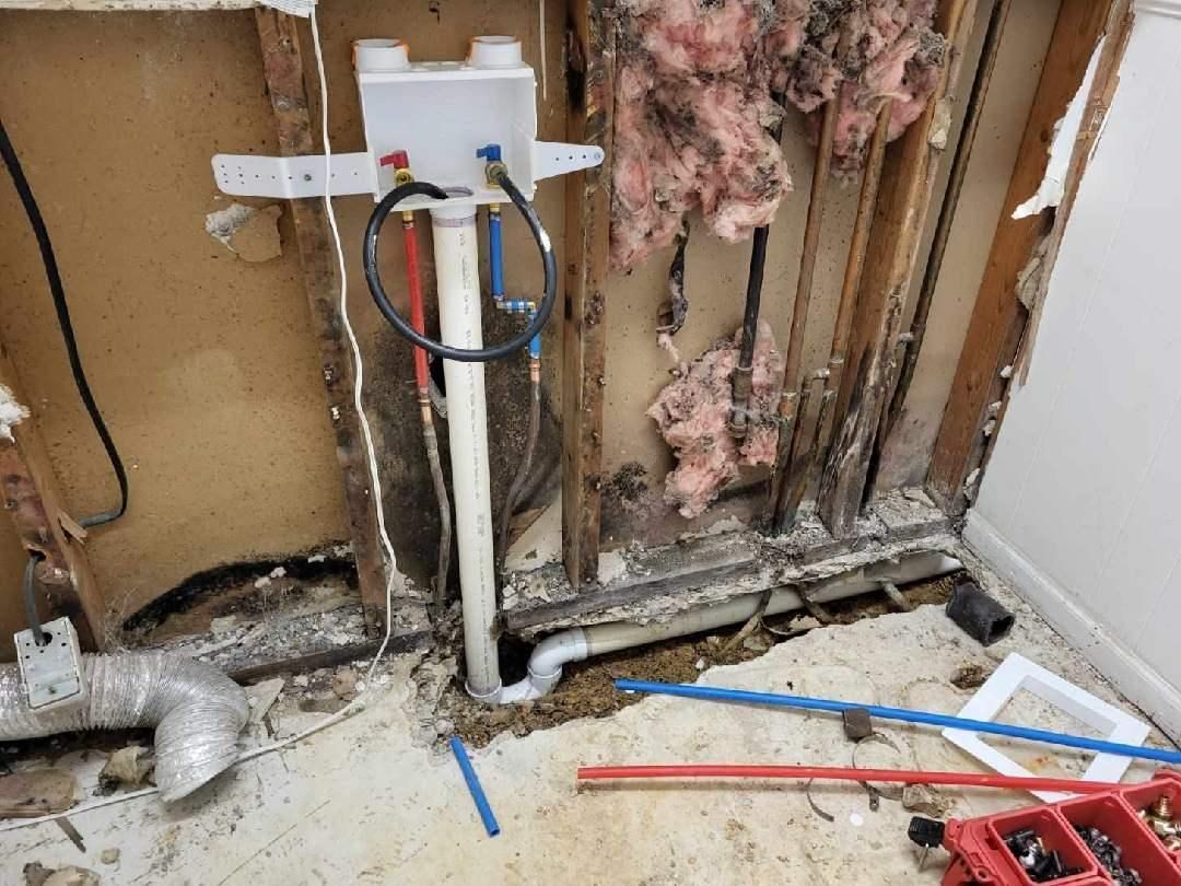 Exposed wall with plumbing pipes and insulation. Possible water damage visible.