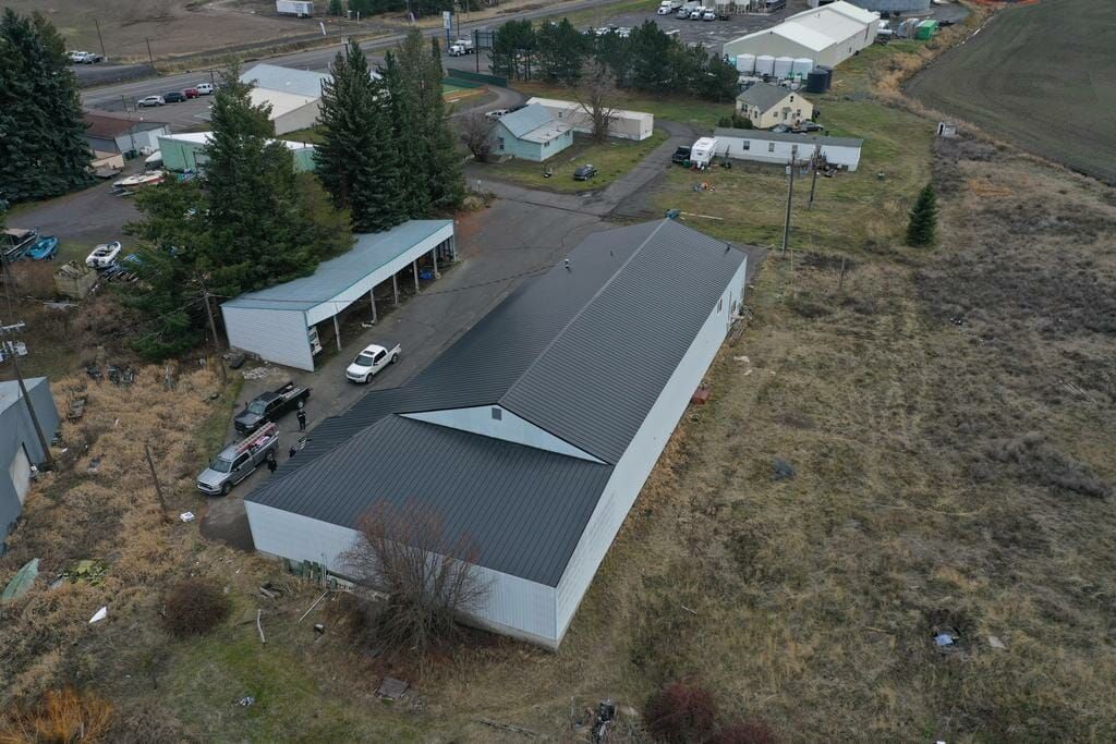 An aerial view of a large white building with a black roof in a field.