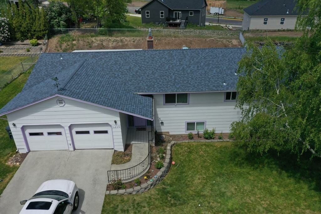 An aerial view of a white house with a blue roof and a car parked in front of it.