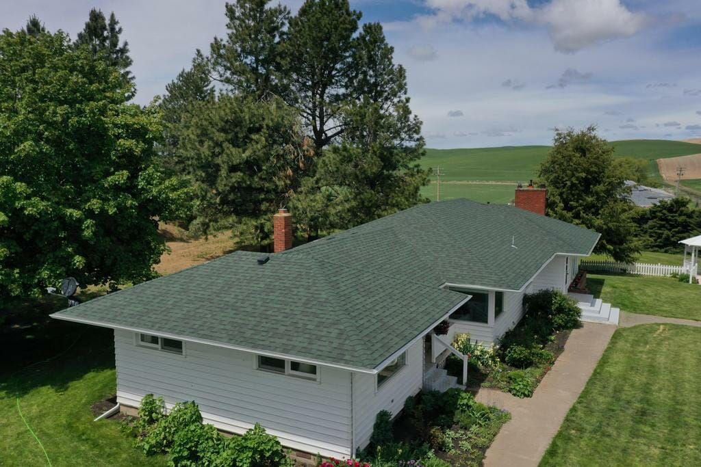 An aerial view of a white house with a green roof