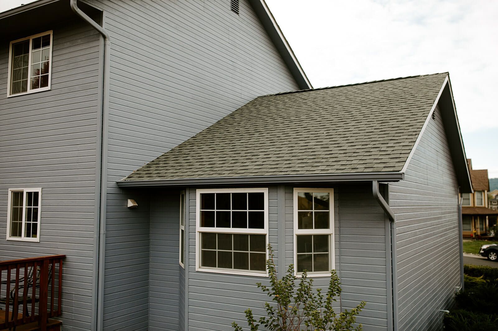 A gray house with a gray roof and white windows