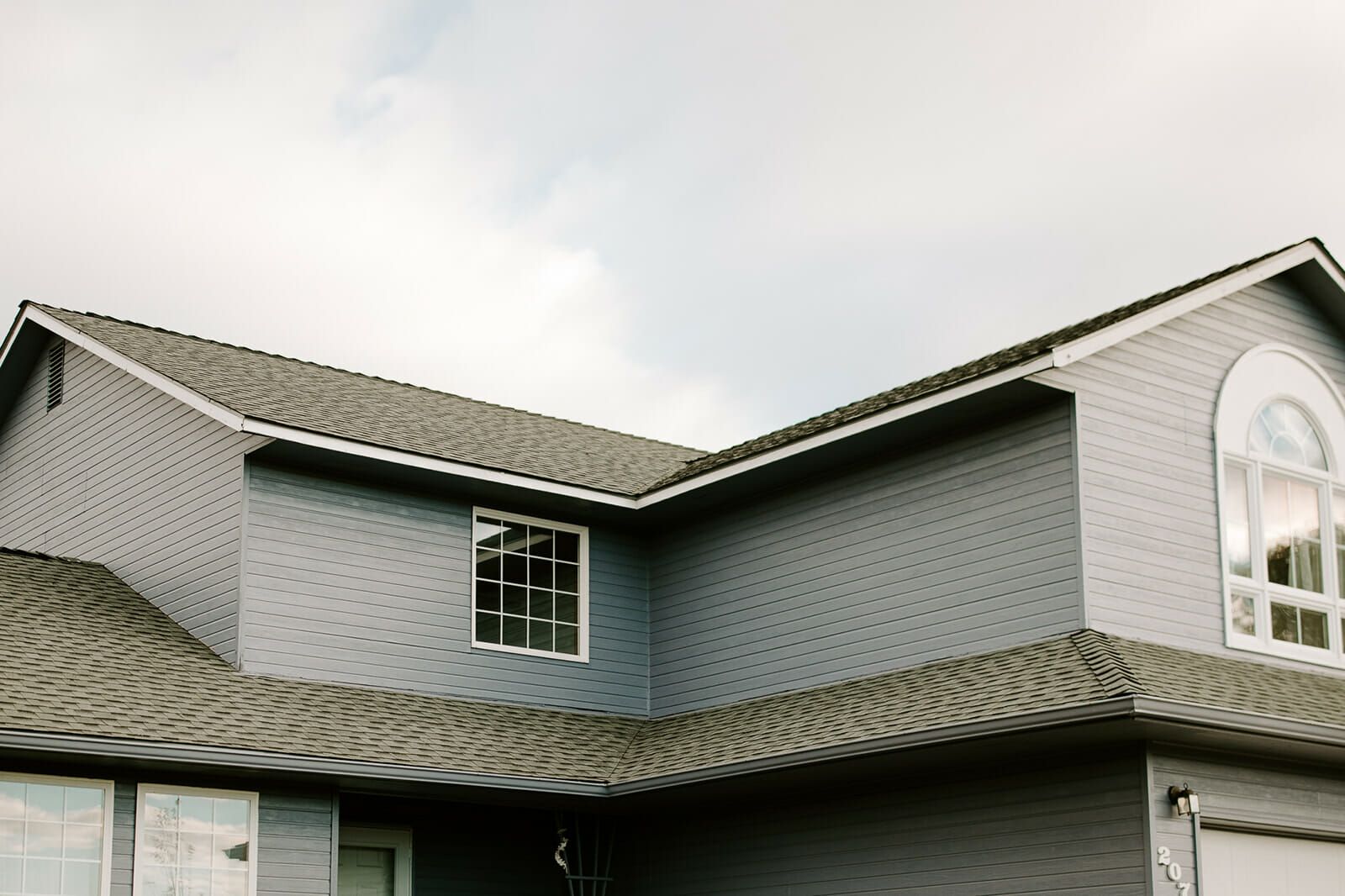 A large gray house with a gray roof and a lot of windows.