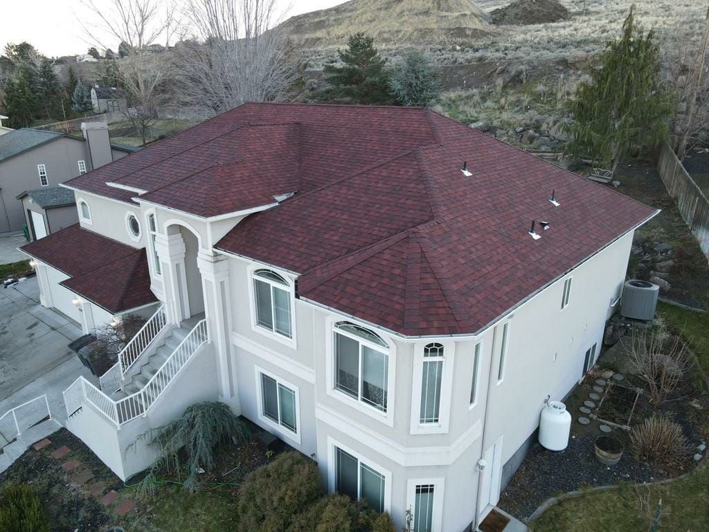 An aerial view of a large white house with a red roof.