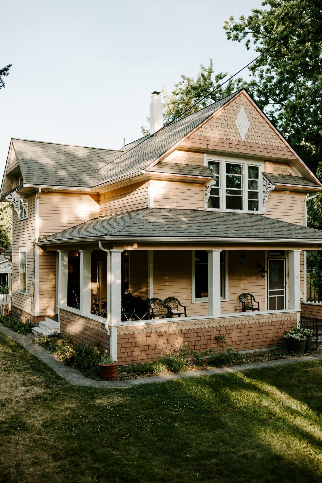 A small brick house with a porch and chairs on it.