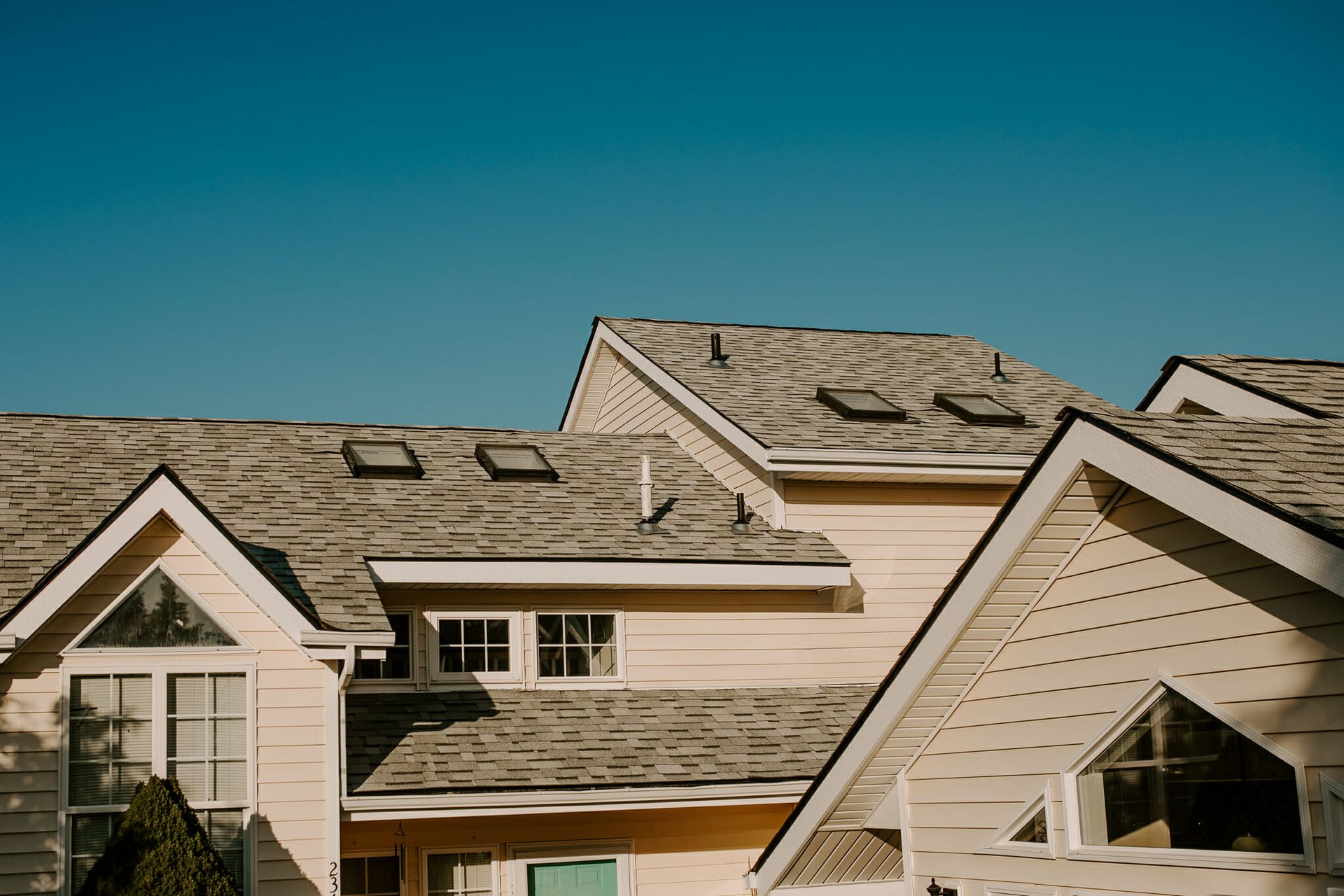 A large house with a gray roof and a blue sky in the background.