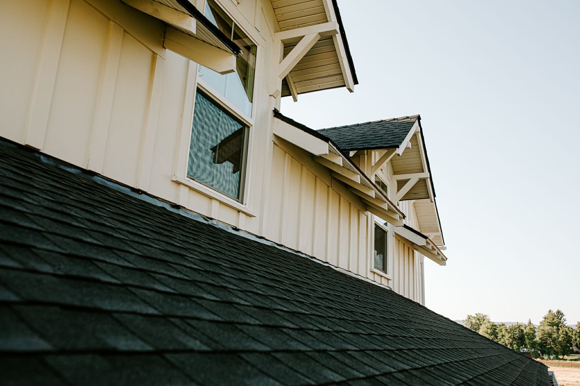 A white house with a black roof and a broken window.