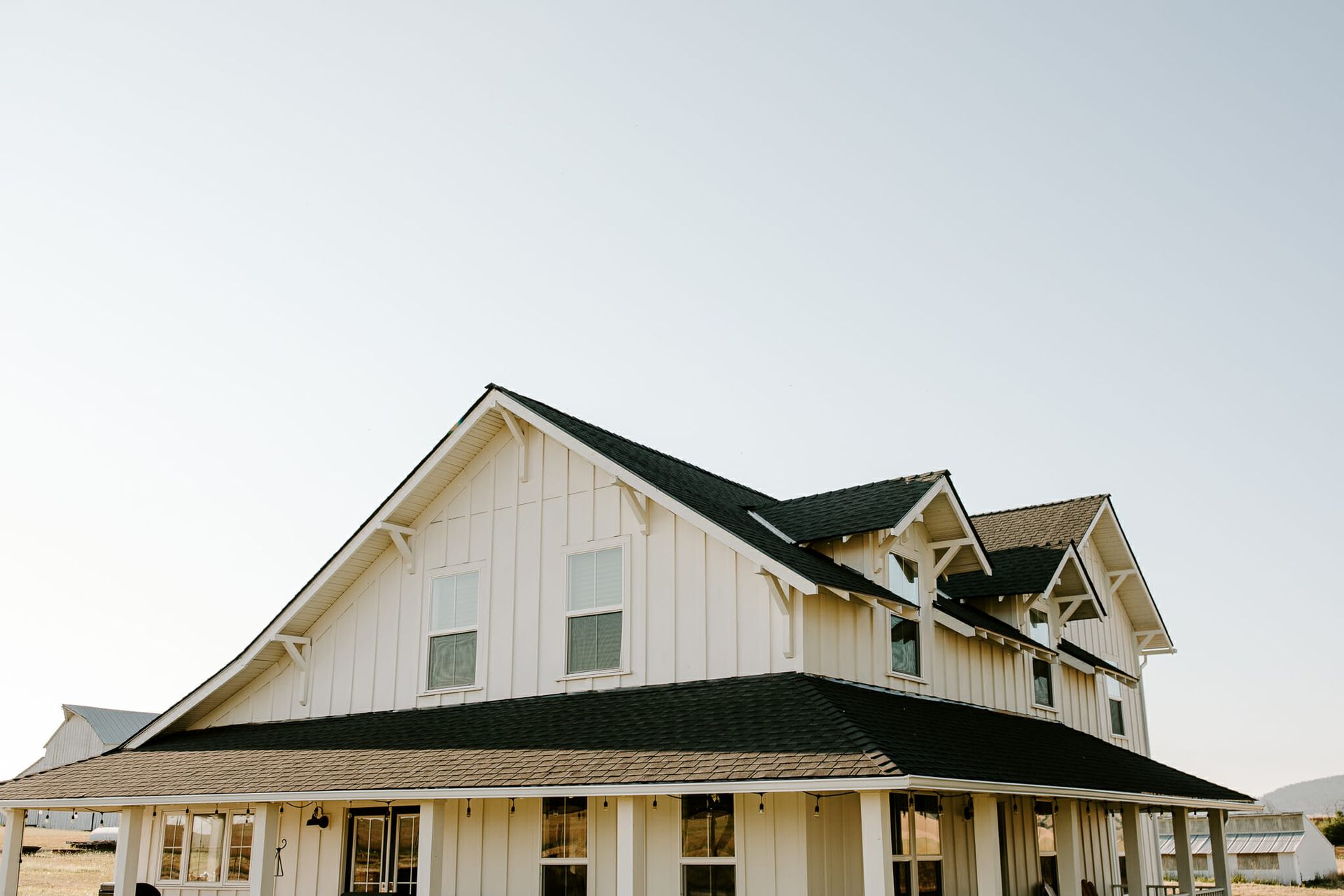 A large white house with a black roof and a porch.